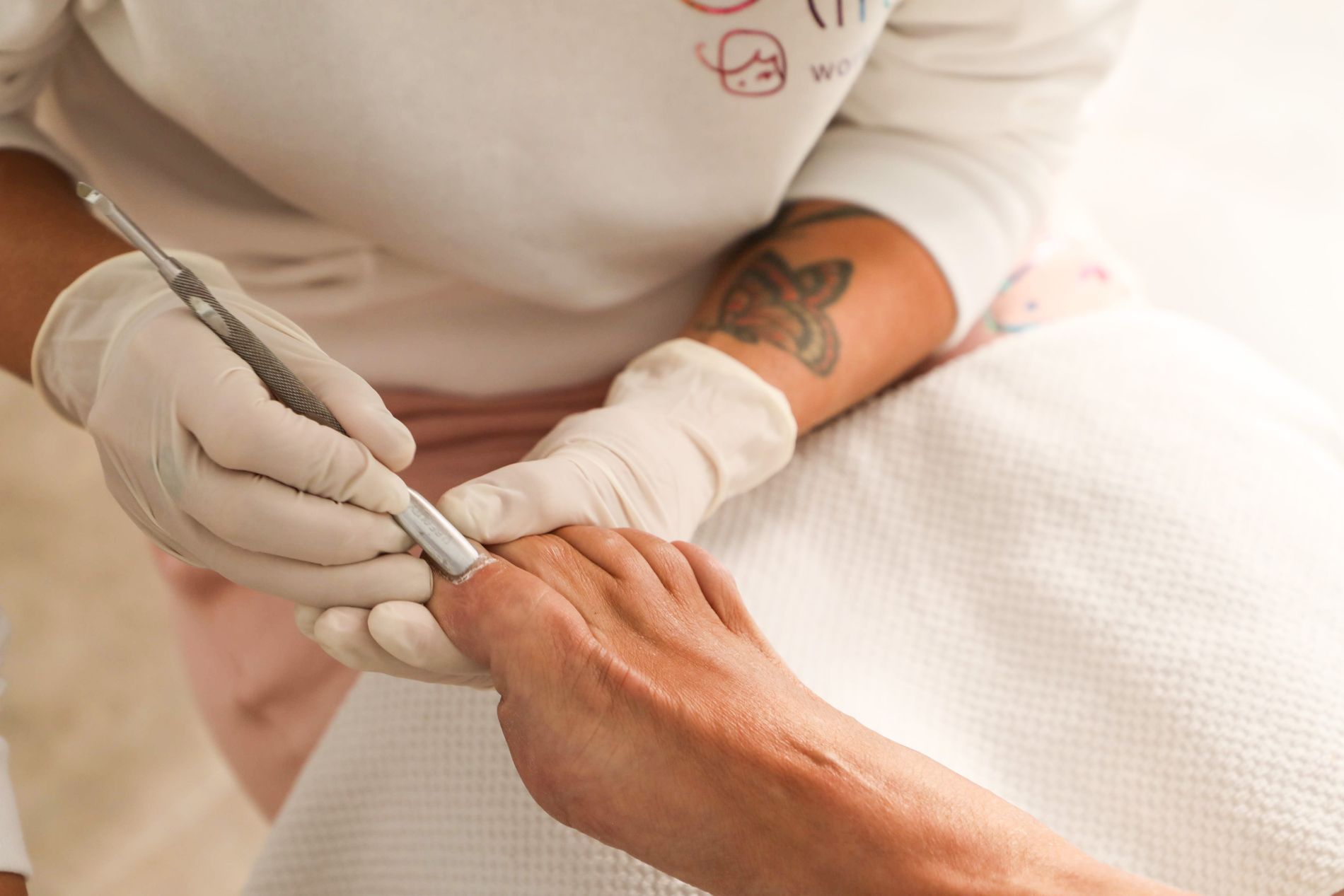 Hände in medizinischen Handschuhen bei der professionellen Nagelpflege